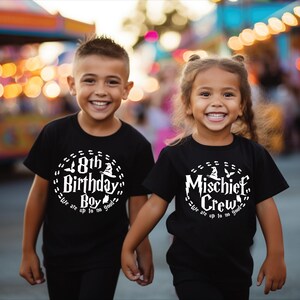May include: Two children wearing black t-shirts with white text. The boy's shirt says "8th Birthday Boy - We are up to no good" and the girl's shirt says "Mischief Crew - We are up to no good".