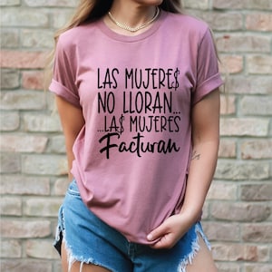 May include: A mauve t-shirt with the text "Las mujeres no lloran... Las mujeres facturan" printed in black.