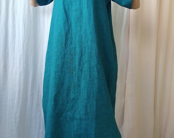 Puede incluir: Un vestido de lino turquesa con cuello en V y mangas cortas. El vestido es holgado y llega a la mitad de la pantorrilla.