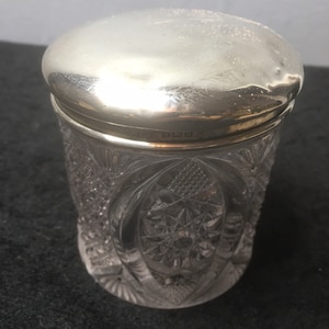 May include: A clear glass jar with a silver lid. The jar has a cut glass design and the lid has a hallmark.