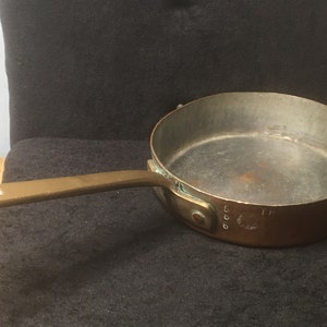 May include: A vintage copper saucepan with a brass handle. The saucepan has a 5 inch diameter and is marked "GOOD"