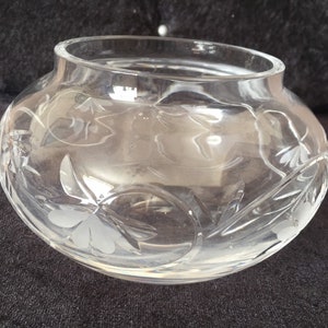 Pode incluir: Uma tigela de vidro transparente com um design floral gravado. A tigela é redonda e tem uma abertura larga.