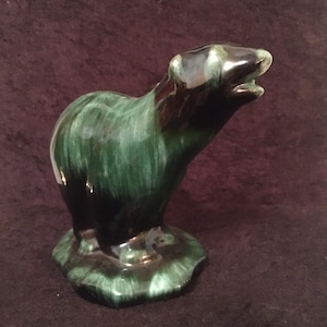 Op de afbeelding: Een groene en zwarte geglazuurde keramische berenfiguur die op een voet staat. De beer kijkt omhoog en heeft een gladde, glanzende afwerking.