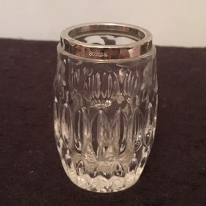 May include: A clear glass bud vase with a silver rim and a decorative pattern. The vase has the number "80008" etched on the side.