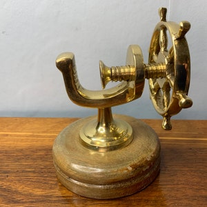 May include: A gold-toned brass nutcracker shaped like a ship's wheel with a wooden base.