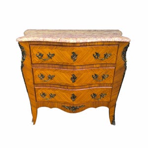 Puede incluir: Cómoda antigua de tres cajones con tapa de mármol. La cómoda tiene un frente curvo y herrajes de latón ornamentados. La madera tiene un acabado marrón claro con un veteado. La tapa de mármol es de color rosa y crema.