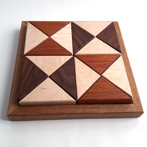 May include: A wooden geometric puzzle with a square frame and 12 triangular pieces. The pieces are made of different types of wood, including maple, walnut, and cherry. The puzzle is a fun and challenging way to exercise your brain.