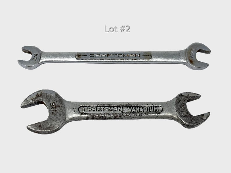 May include: Two silver-colored metal Craftsman wrenches labeled Lot #2. The top wrench features 1/4 and 5/16 inch open ends. The bottom wrench is marked Craftsman Vanadium and features 7/16 inch open ends on both sides of the tool head.
