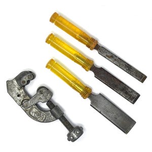 May include: A collection of vintage woodworking tools, including three chisels with yellow handles and a metal pipe cutter. The chisels have metal blades and the pipe cutter is silver.