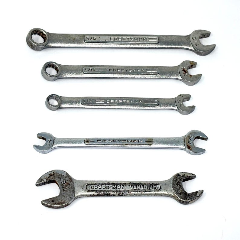 May include: A set of five silver-colored metal Craftsman wrenches arranged horizontally. Four are combination wrenches with box and open ends, and one is a double open-ended wrench. Each tool features the embossed Craftsman brand name.