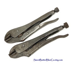May include: Two vintage locking pliers, also known as vise grips, are displayed on a white background. The tools are made of metal and show signs of wear. The jaws are closed, and the handles have adjustment screws. The text "SweetButterBlueCo.etsy.com" is visible.