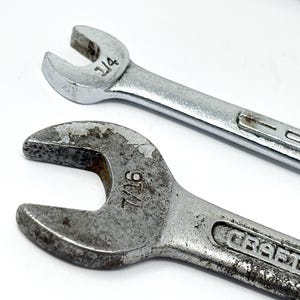 May include: Two silver-colored metal wrenches with open ends. The top wrench is marked 1/4 inch and the bottom wrench is marked 7/16 inch. Both wrenches feature the brand name Craftsman embossed on the handle. The bottom wrench shows signs of wear.