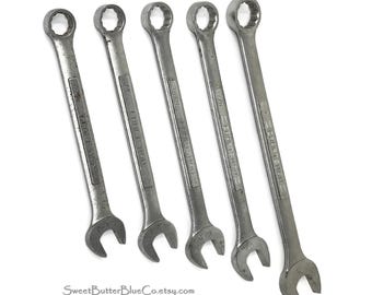 May include: A set of five silver-colored metal combination wrenches arranged in a row. Each tool features a closed box end and an open end, with the brand name Craftsman and specific size markings embossed on the handle of each individual wrench.
