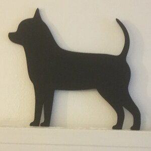 Op de afbeelding: Zwarte silhouet van een Chihuahua-hond die op een wit oppervlak staat.