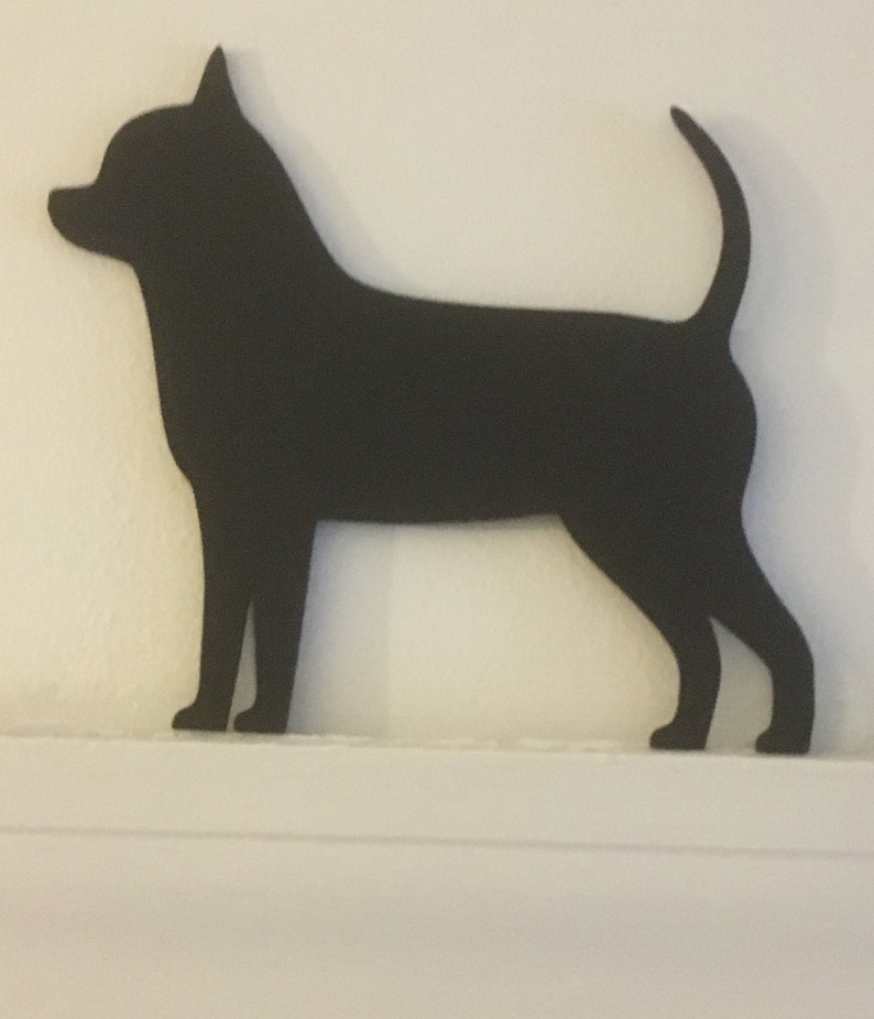 Op de afbeelding: Zwarte silhouet van een Chihuahua-hond die op een wit oppervlak staat.