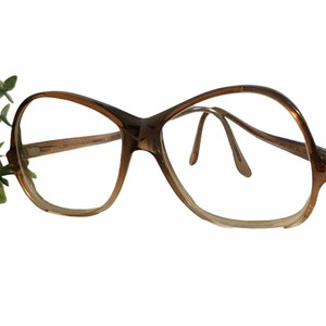 May include: Brown plastic framed glasses with a rounded, oversized shape. The glasses have clear lenses.