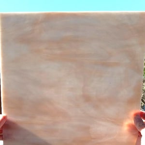 May include: A sheet of translucent, light pink and white glass with a marbled effect. The glass is smooth and has a slight sheen.