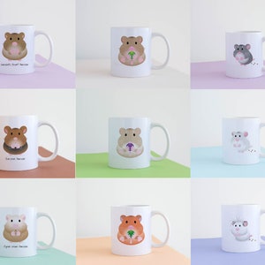 Op de afbeelding: Negen witte keramische mokken met verschillende hamsterillustraties. Elke mok heeft een hamster die een stuk voedsel vasthoudt, met de naam van de hamster eronder gedrukt. De namen zijn: 'Dwerghamster', 'Syrische hamster', 'Campbells dwerghamster', 'Russische dwerghamster', 'Chinese dwerghamster', 'Winterwitte dwerghamster', 'Roborovski-dwerghamster', 'Teddy-dwerghamster' en 'Hybride dwerghamster'.