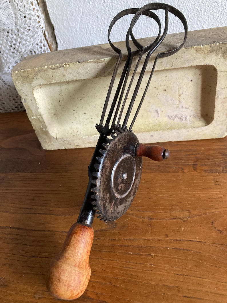 Pu&ograve; includere: Sbattitore per uova vintage a manovella con manico in legno e pi&ugrave; fruste in metallo. Lo sbattitore ha un meccanismo a ingranaggi ed &egrave; in metallo.