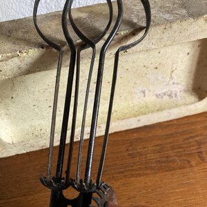 Pu&ograve; includere: Sbattitore per uova antico a manovella con tre fruste in metallo e un manico in legno. Lo sbattitore per uova &egrave; in metallo nero e ha un design a forma di ingranaggio.