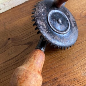 Pu&ograve; includere: Un trapano a mano vintage con un ingranaggio in metallo nero e due manici in legno. Il trapano &egrave; in buone condizioni con alcuni segni di usura.