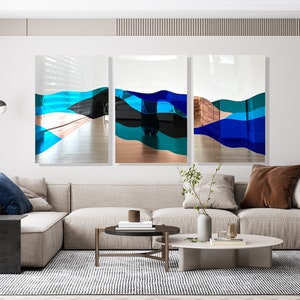 Op de afbeelding: Een modern woonkamerinterieur met een hoekbank, een salontafel en een driedelig abstract kunstwerk in blauwe, turquoise en koperkleurige tinten.