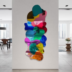 Könnte beinhalten: Ein farbenfrohes abstraktes Wandkunstwerk aus mehreren überlappenden Formen in verschiedenen Farben, darunter Pink, Blau, Grün, Gelb und Orange. Die Formen sind in einem vertikalen Stapel angeordnet und schaffen ein dynamisches und modernes Design.