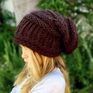 May include: A brown knitted beanie with a slouchy fit. The beanie is made with a thick yarn and has a cable knit pattern.