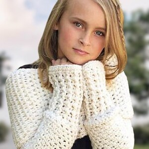 May include: A young person wearing a white crocheted shrug with long sleeves. The shrug is made with a delicate open stitch pattern.