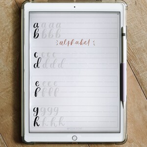 May include: A digital tablet screen displaying a handwritten alphabet in black ink on a white background. The letters are written in cursive and are spaced out evenly. The text "alphabet" is written in cursive in a light brown color. The text "@POCKY FONT" is written in black at the bottom of the screen.