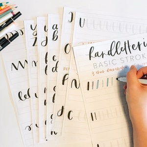 May include: A set of printable worksheets for practicing basic hand lettering strokes. The worksheets feature a variety of lines and shapes, with instructions for thick downstrokes and thin upstrokes. The image shows a hand holding a pen and practicing the strokes on one of the worksheets.