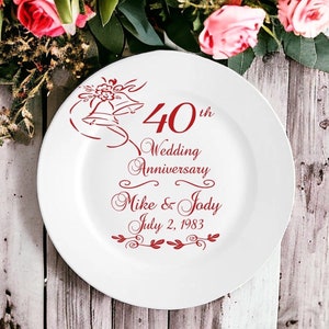 May include: White ceramic plate with a red design celebrating a 40th wedding anniversary. The design includes two bells, the text "40th Wedding Anniversary", the names "Mike & Jody", and the date "July 2, 1983".