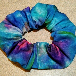 May include: A blue, purple, and green tie-dye scrunchie made of fabric.