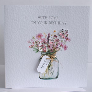 May include: A handmade birthday card with a watercolor illustration of a bouquet of pink and white flowers in a mason jar. The card reads "WITH LOVE ON YOUR BIRTHDAY" and has a tag that says "Wendy".
