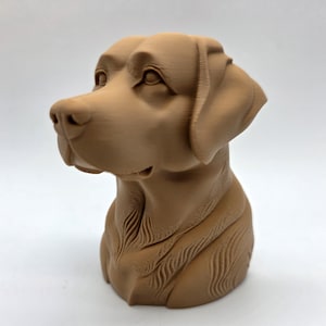 May include: A brown, 3D-printed bust of a Labrador Retriever dog. The sculpture features detailed facial features, including the eyes, nose, and ears. The dog's head and upper chest are visible, showcasing the breed's characteristics.