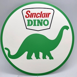May include: A round white sign with a green border featuring a green dinosaur silhouette. The sign has the Sinclair Oil logo at the top, with the words "Sinclair" in red and "DINO" in green.