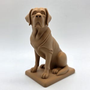 May include: A brown Labrador Retriever statue in a seated position. The dog is on a square base and has a smooth, matte finish. The statue is a solid color and has detailed features.