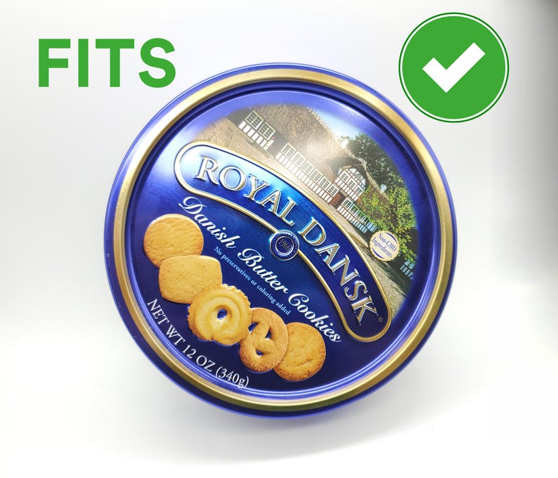 May include: A round blue tin of Royal Dansk Danish Butter Cookies. The tin has a gold rim and features an image of a building and several cookies. The text "Royal Dansk Danish Butter Cookies" is displayed on the tin. The net weight is 12 oz (340g).