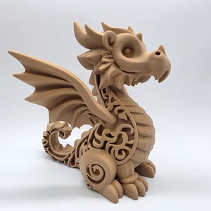 May include: A tan-colored dragon figurine with detailed wings and decorative scrollwork. The dragon is in a seated position, with its head turned slightly to the right. The figurine is made of a solid material and has a smooth finish.