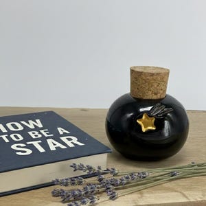 Könnte beinhalten: Eine weiße Keramik-Tasse mit schwarzem Henkel und dem Text "But First, Coffee" in handschriftlichem Stil. Die Tasse steht auf einer weißen Oberfläche. Die Tasse hat wahrscheinlich 325 ml.