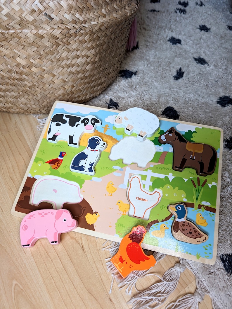 Peut inclure: Un puzzle en bois repr&eacute;sentant des animaux de la ferme : vache, mouton, chien, cheval, cochon, poulet et canard. Les pi&egrave;ces color&eacute;es s'ins&egrave;rent dans les espaces correspondants du plateau. Le mot "Chicken" est imprim&eacute; sur le puzzle.