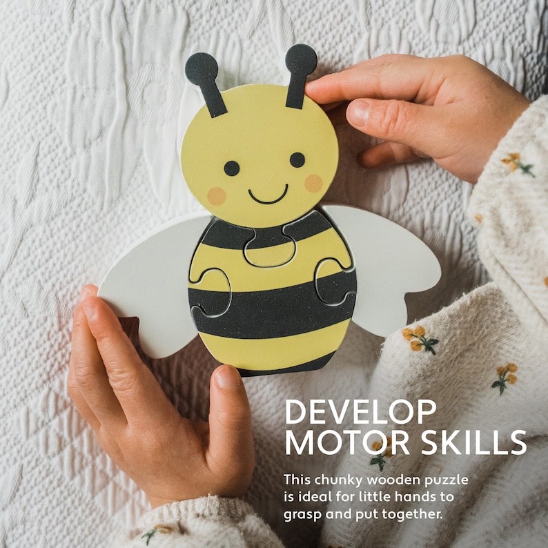 May include: A wooden puzzle shaped like a bee with yellow and black stripes. The bee has a smiling face and large, white wings. The puzzle is made up of five pieces and is ideal for developing fine motor skills.