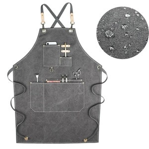 May include: A gray canvas apron with multiple pockets and a leather strap. The apron has a water-resistant finish.