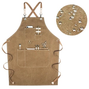 May include: A brown canvas apron with multiple pockets and a leather strap. The apron has a cross-back design and is water-resistant.