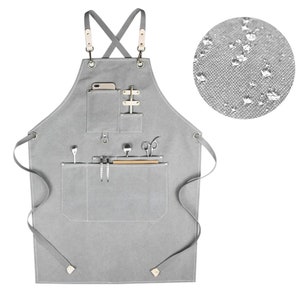 May include: A gray canvas apron with multiple pockets and a phone pocket. The apron has adjustable straps and is made of water-resistant material.