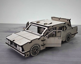 Könnte beinhalten: Ein detailliertes Holzmodellauto mit geöffneten Türen. Das Auto besteht aus hellem Holz und weist komplizierte Ausschnitte für Fenster, Räder und andere Details auf. Das Modellauto ist im klassischen Limousinenstil gehalten.