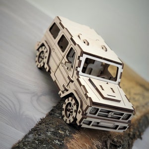 K&ouml;nnte beinhalten: Ein Holzmodell eines hellbraunen SUV mit detailliertem Innenraum und einem Mercedes-Benz-Logo an der Front.