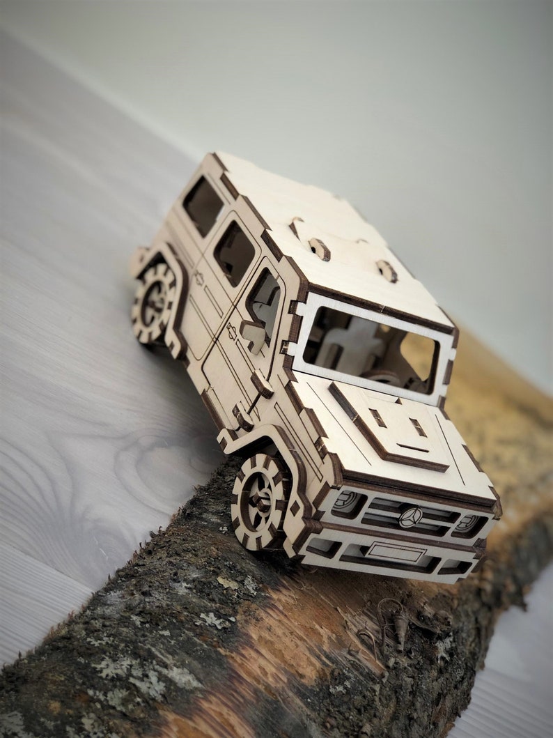 K&ouml;nnte beinhalten: Ein Holzmodell eines hellbraunen SUV mit detailliertem Innenraum und einem Mercedes-Benz-Logo an der Front.