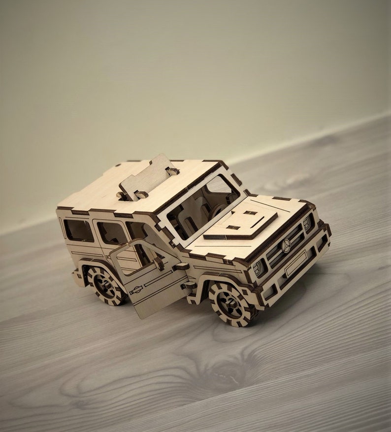 K&ouml;nnte beinhalten: Ein Holzmodell eines Autos mit offener T&uuml;r. Das Modell ist aus hellbraunem Holz gefertigt und hat ein detailliertes Design. Das Auto hat einen schwarzen K&uuml;hlergrill und Scheinwerfer.