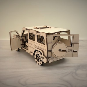 K&ouml;nnte beinhalten: Ein Holzmodell eines hellbraunen SUV mit ge&ouml;ffneten T&uuml;ren. Das Modell hat ein Reserverad hinten und einen detaillierten Innenraum.